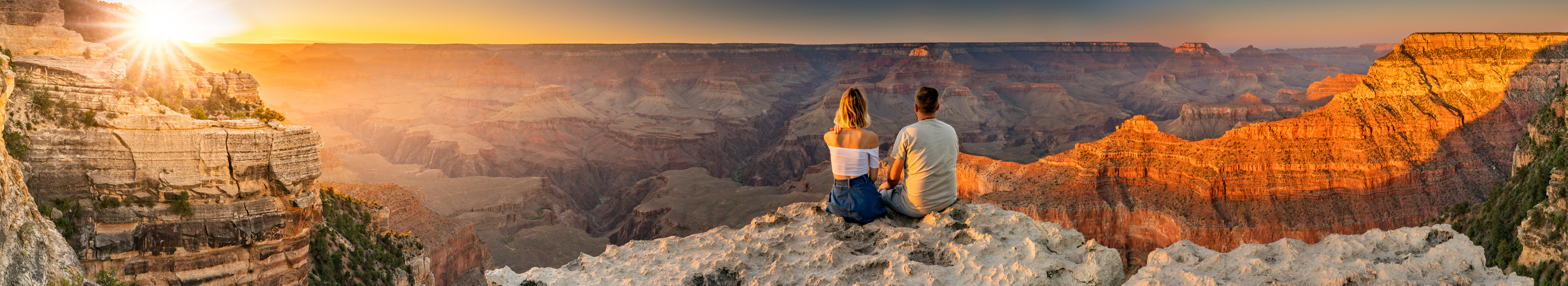 Ein Paar sitzt am Grand Canyon bei Sonnenuntergang