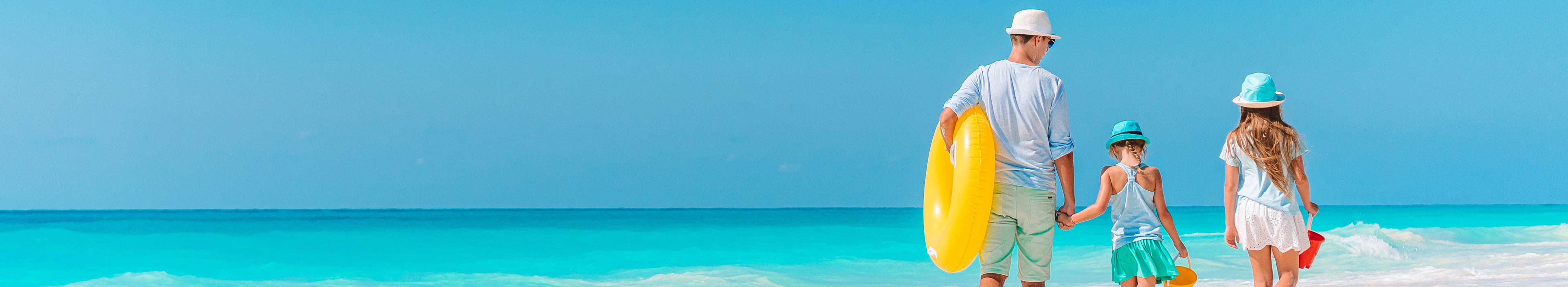 Eine Familie läuft im Urlaub am Strand entlang.