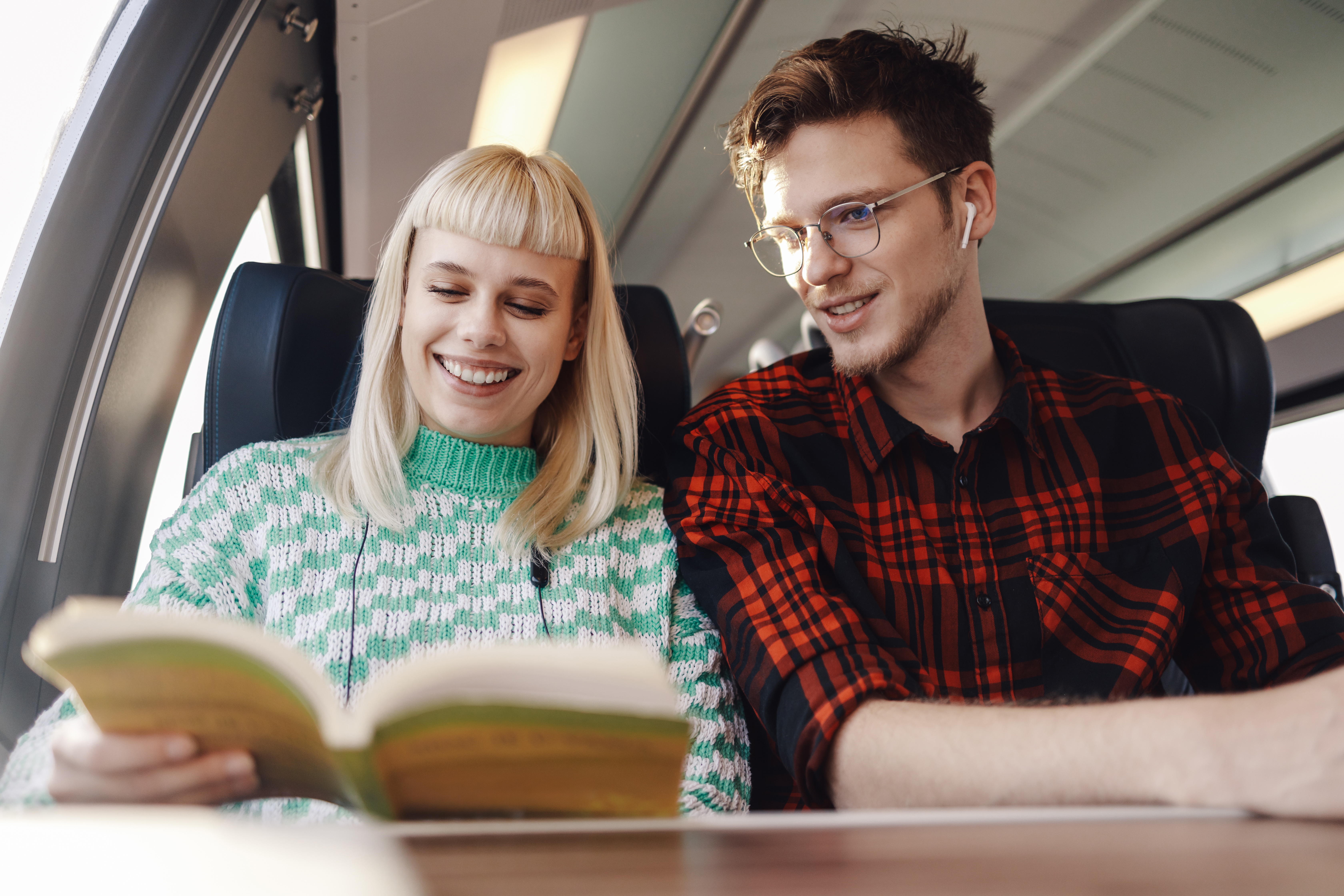 Ein Pärchen in einem Zug liest ein Buch.