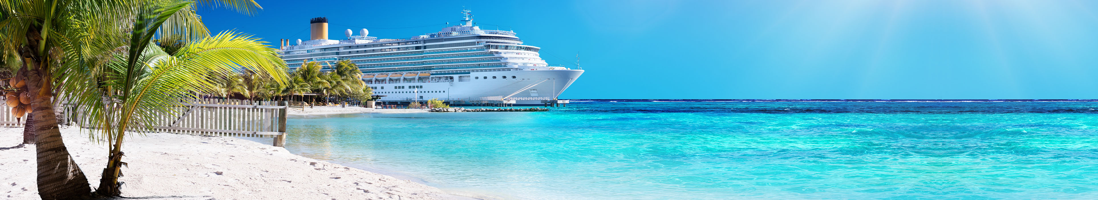 Kreuzfahrtschiff an weißem Karibikstrand im türkisfarbenem Wasser
