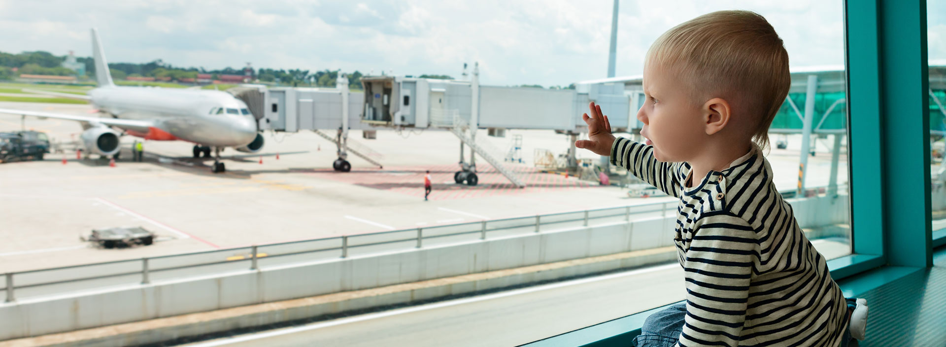 Ein Kleinkind am Flughafen, schaut auf ein Flugzeug