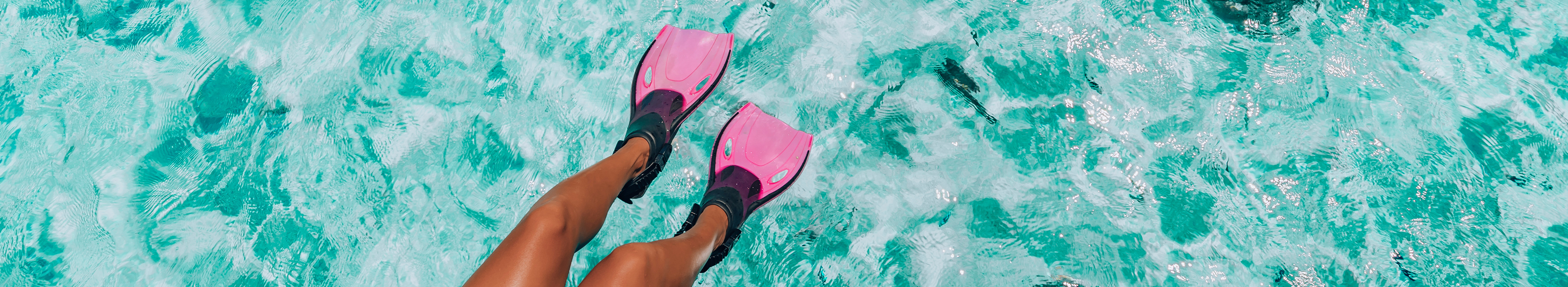 Beine im Meer mit pinken Taucherflossen