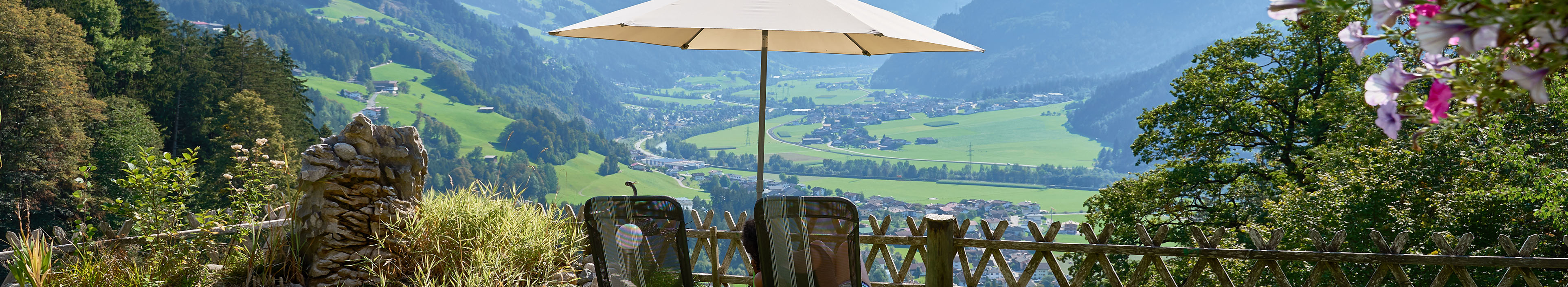 Zwei Liegestühle mit Sonnenschirm in Österreich mit Blick in die Berge.