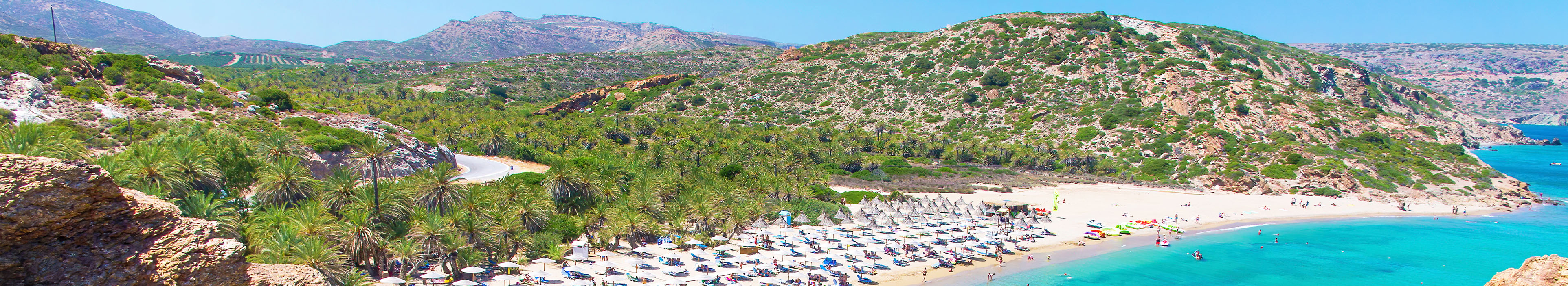 Strand auf Kreta, mit Sonnenschirmen und Liegen.