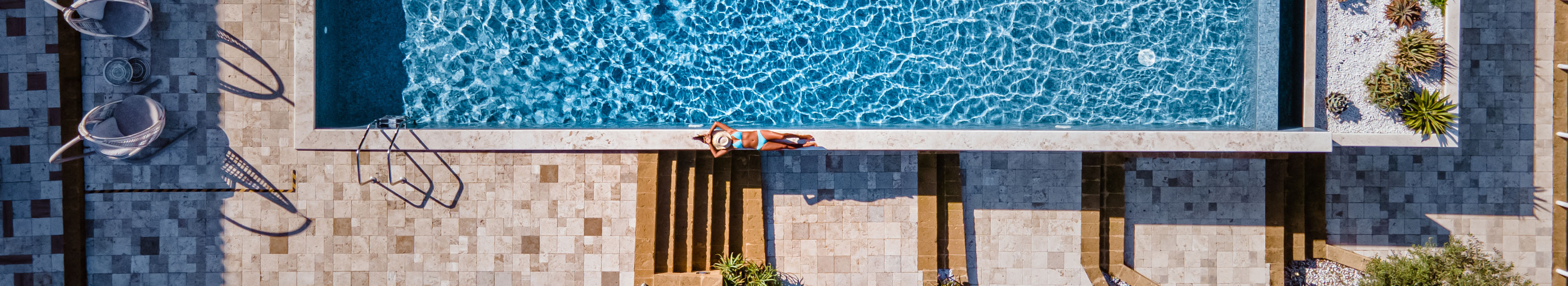 Hotel auf Sizilien, ein Mann schwimmt in einem Pool. Eine Frau liegt am Beckenrand.