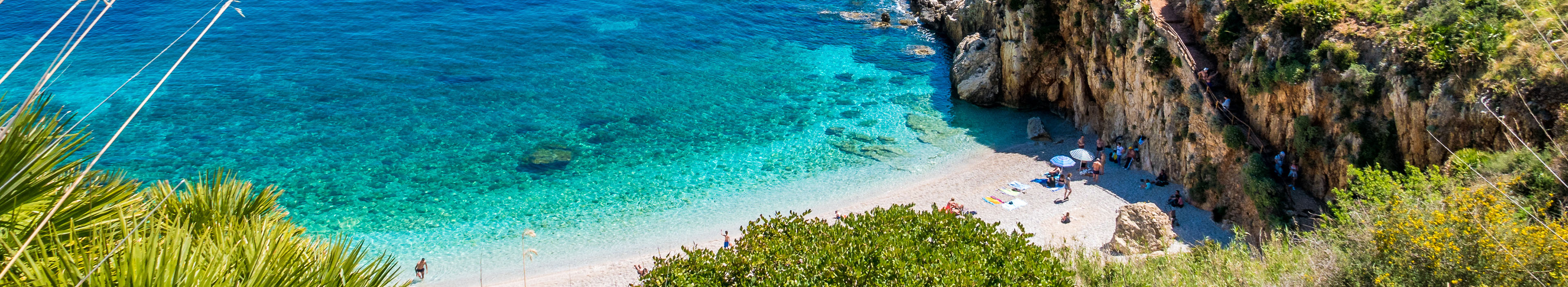 Küstenabschnitt auf Sizilien, blaues Meer, Strand und Felsen.
