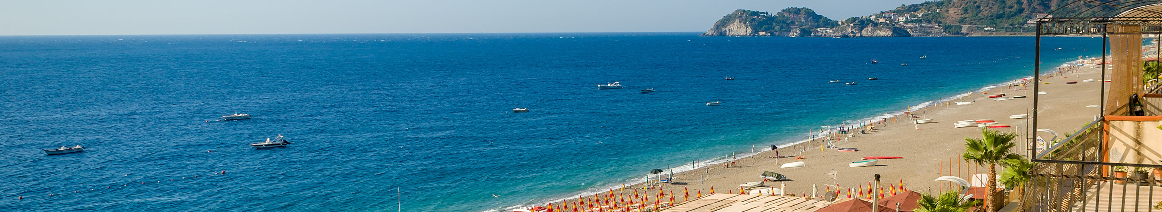 Strand auf Sizilien, Sonnenliegen, Sonnenschirme, Palmen, Boote auf dem Meer.