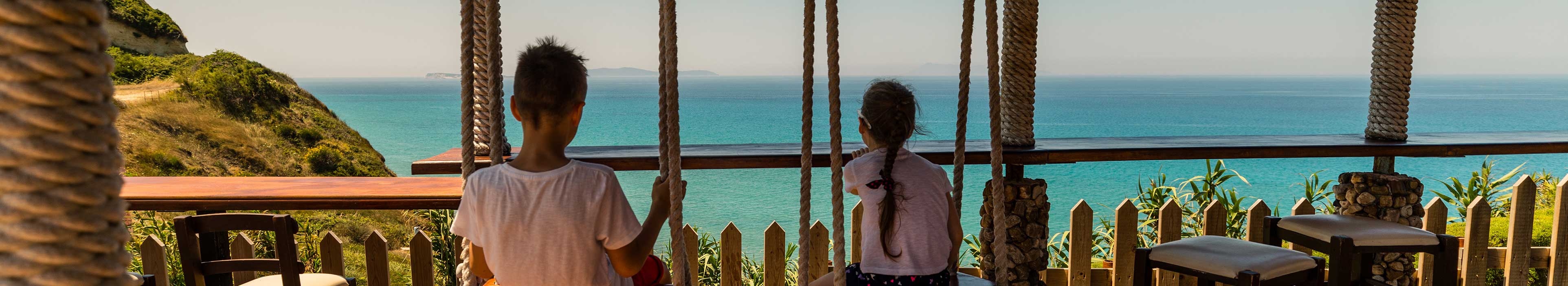 Kinder haben Spaß auf der Schaukel mit herrlichem Blick auf das Meer auf Korfu.