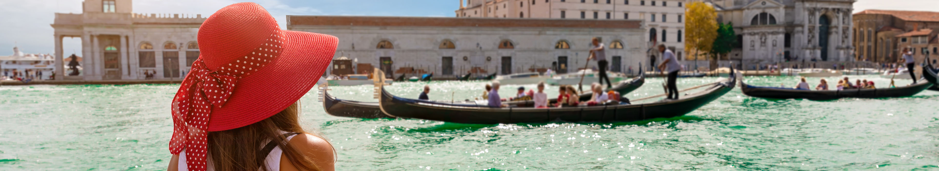 Frau am Canal Grande in Venedig schaut auf eine Gondel.