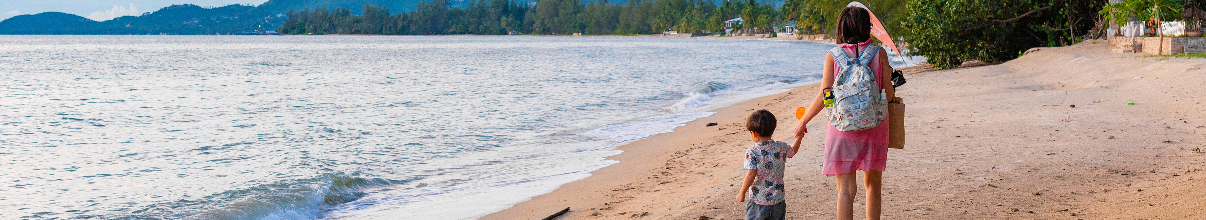 Mutter und Kind laufen am Strand im Urlaub mit Lidl Reisen am Strand von Koh Samui