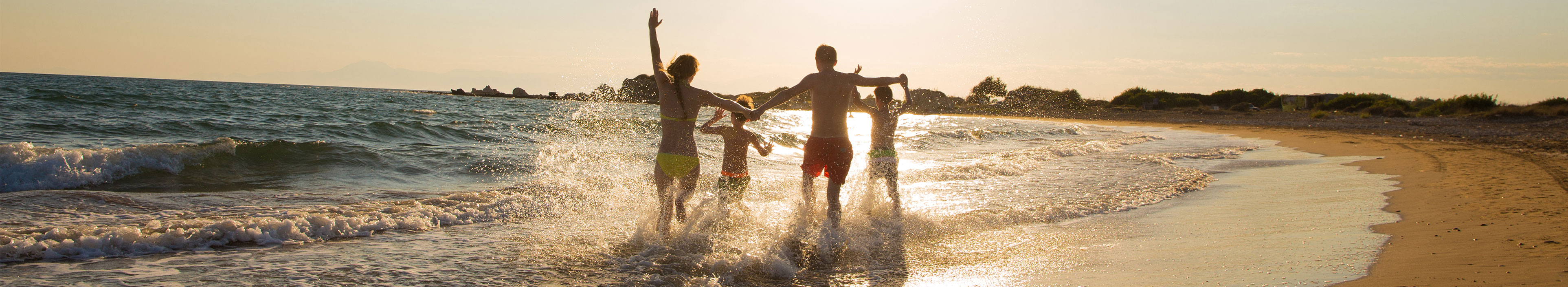 Eine Family läuft am Strand während des Sonnenuntergangs.