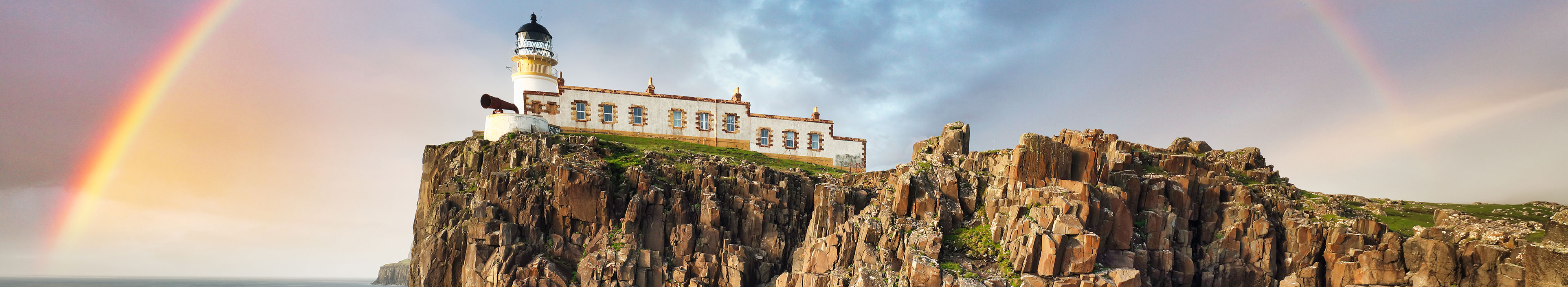 Küste in England mit Leuchtturm und Regenbogen