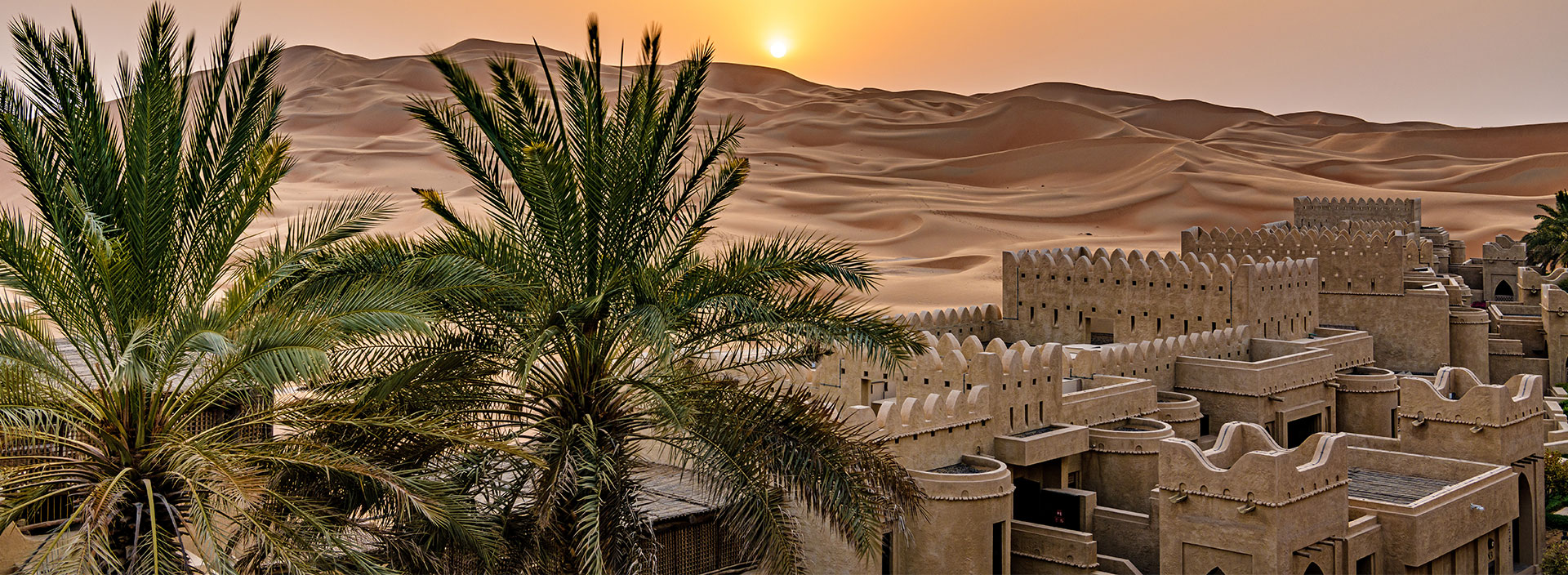 Eine Oase mit Palmen und einem Gebäudekomplex in der Wüste der Vereinigten Arabischen Emirate