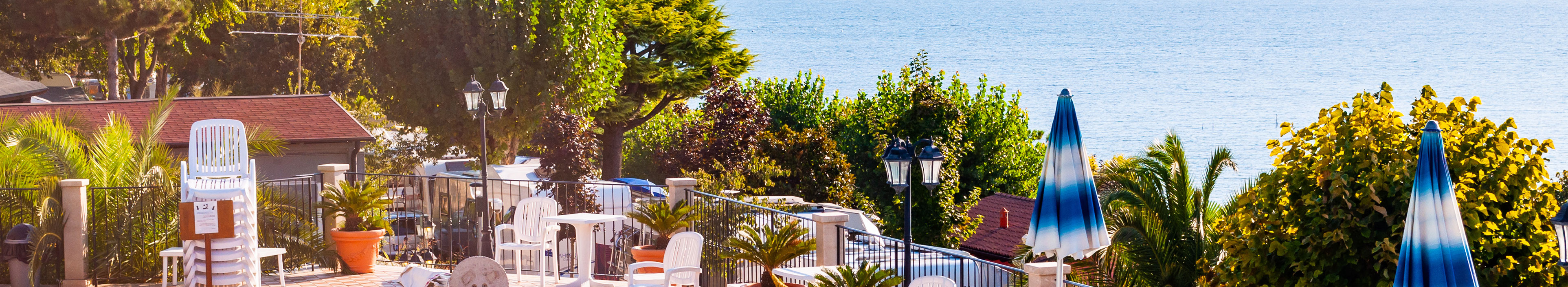 Blick auf ein Hotel am Gardasee, mit Pool, Schirmen und Sitzmöglichkeiten.