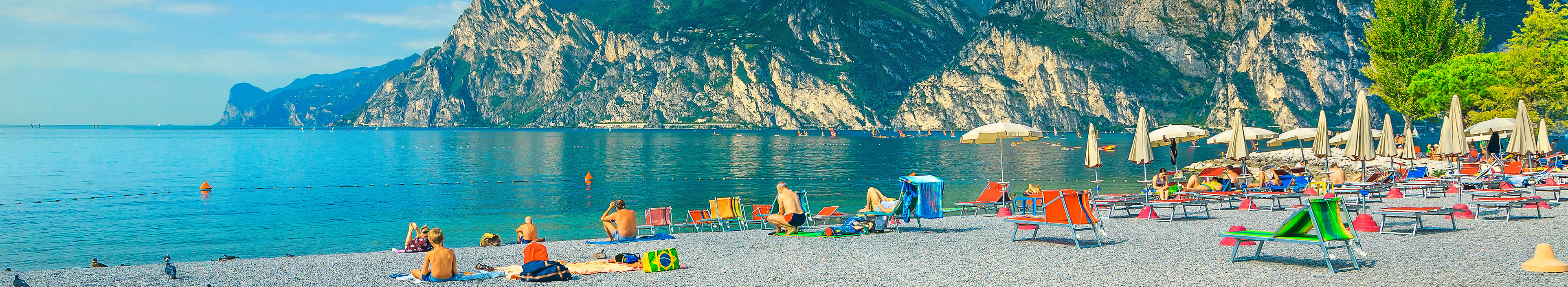 Strand am Gardasee, Liegen, Sonnenschirme und Badegäste.