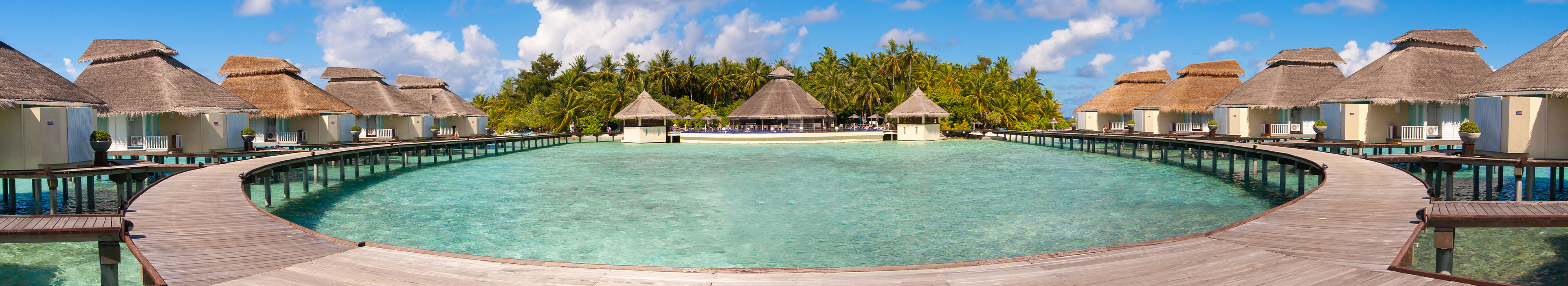 Hotel auf den Malediven, türkisblaues Meer, Palmen und Hütten am Strand