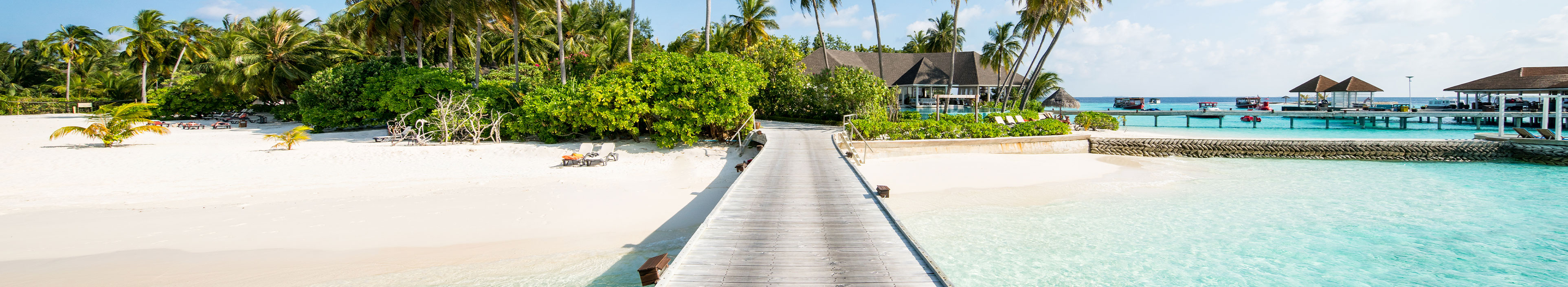 Urlaub Malediven. Heller Holzsteg der sich vom weißen Strand ins türkisfarbene Meer zieht.