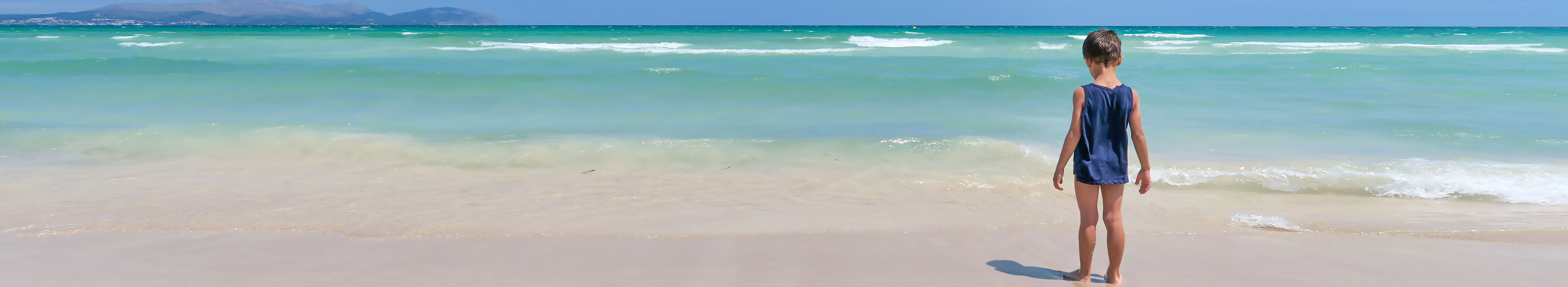 Ein Junge steht am Strand auf Mallorca