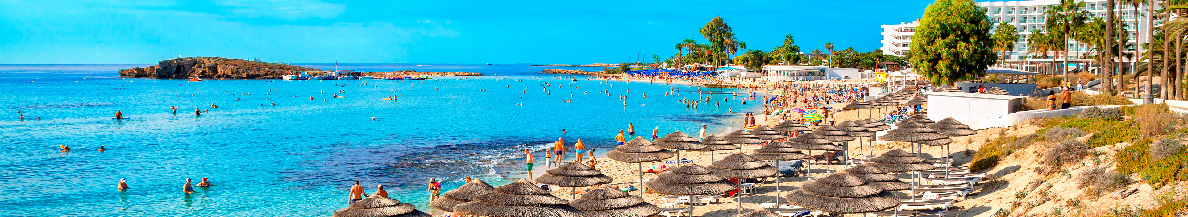 Blick auf einen Strand auf Zypern, Meer, Sand und Sonnenschirme mit Liegen