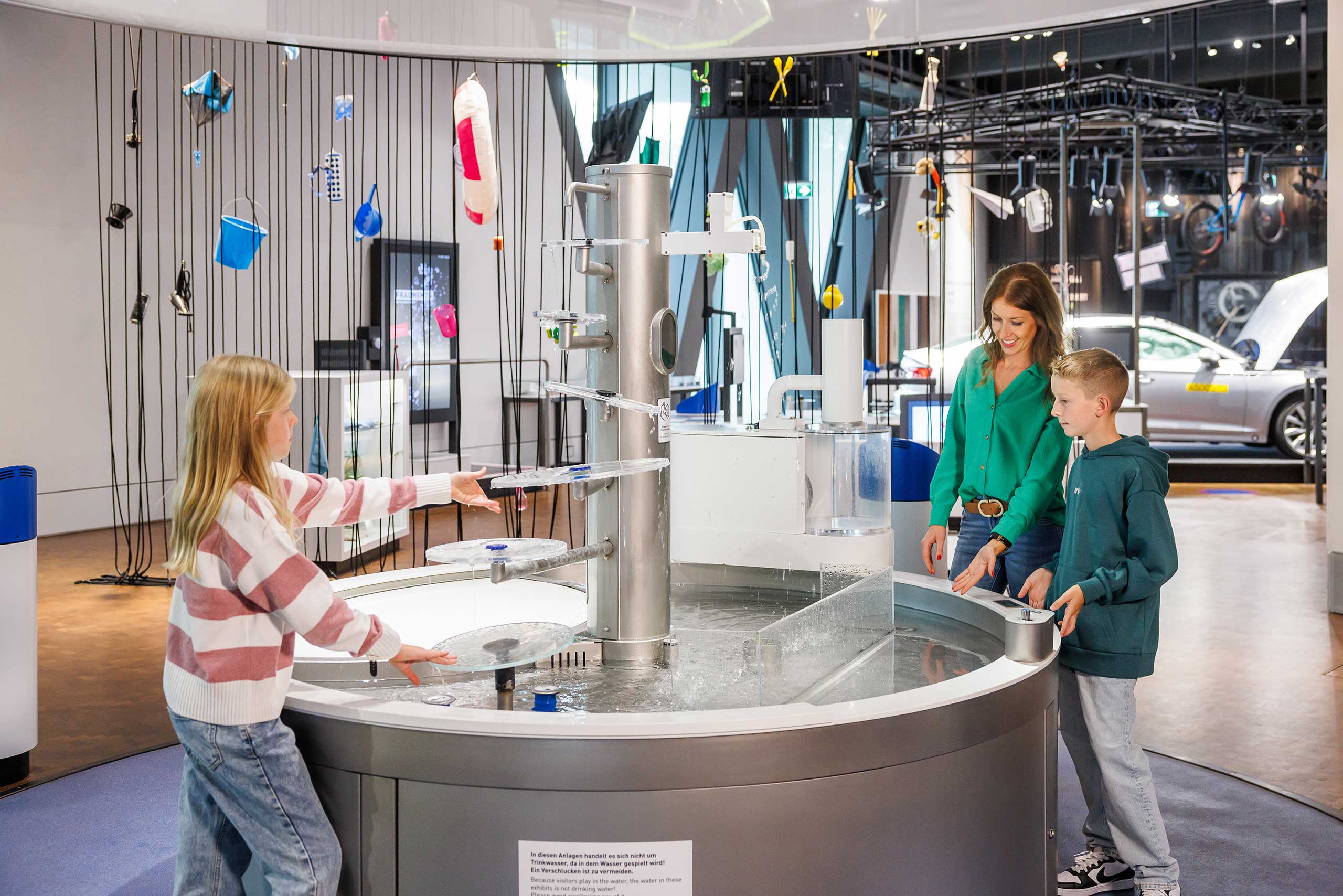 Eine Mutter und ihre zwei Kinder spielen an einer Ausstellung in der experimenta.