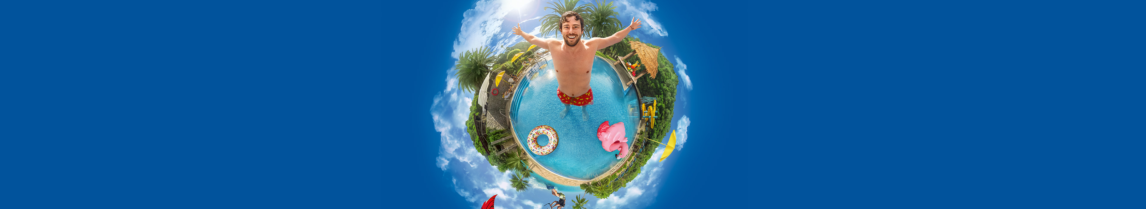 Mann in einem Swimmingpool, um ihn herum Palmen, ein Kitesurfer, Sonnenschirme.