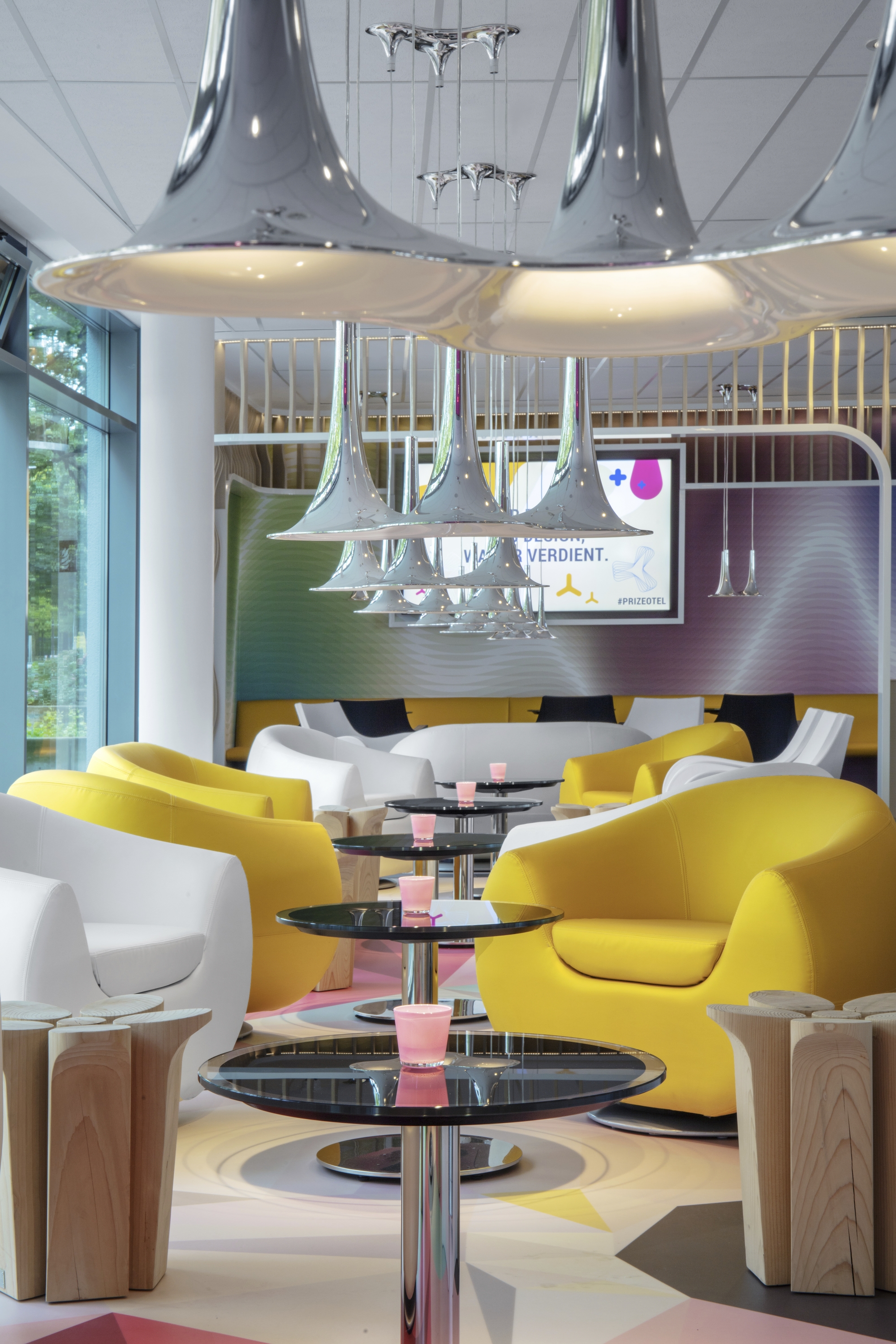 Bunte Hotel-Lobby mit gelben Sesseln und auffaelligen Lampen.